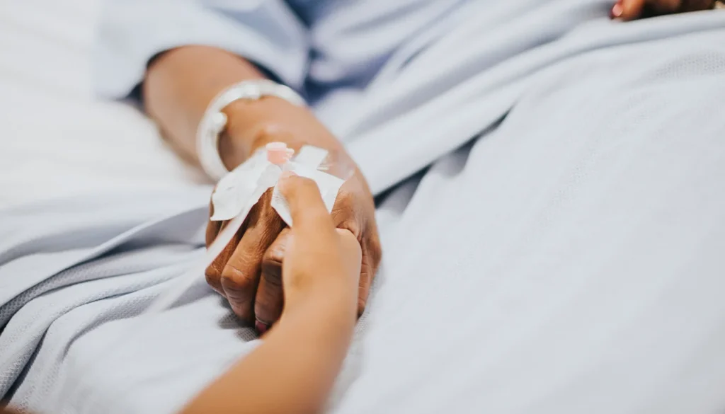 Loving hand holding a patient's hand with an IV catheter.